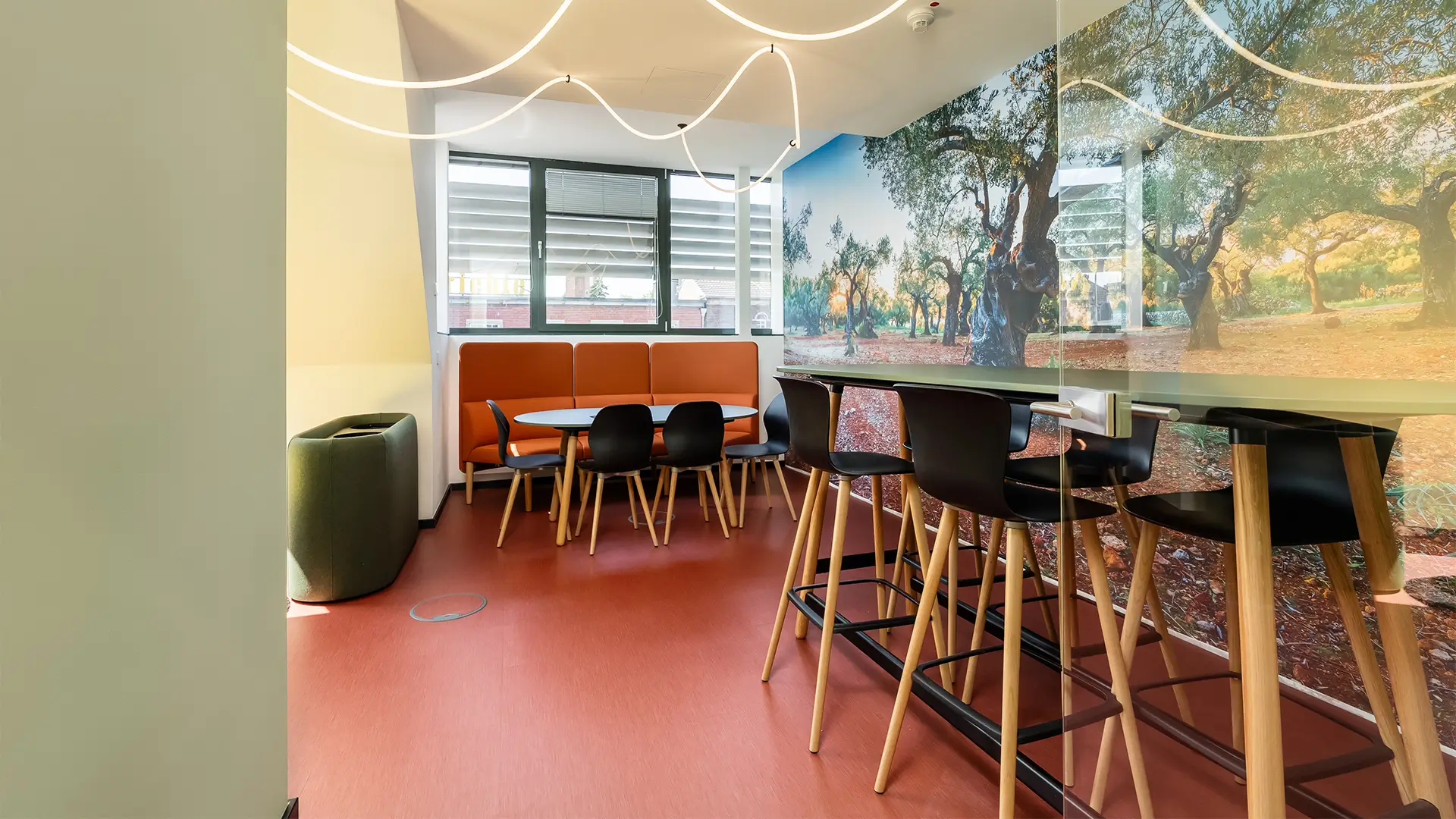 Modern gestalteter Aufenthaltsbereich mit Sitzgelegenheiten, Hochtisch und großflächiger Wandgestaltung.
