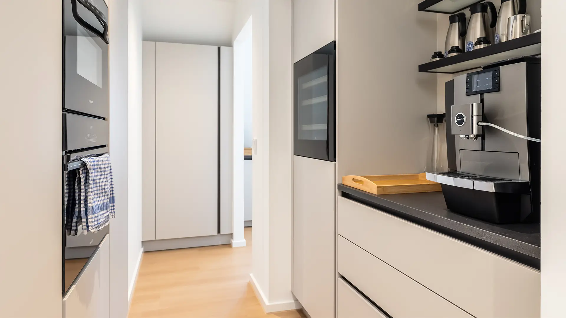 Moderne Teeküche mit Kaffeemaschine, Einbauschränken und funktionaler Ausstattung für Mitarbeitende.