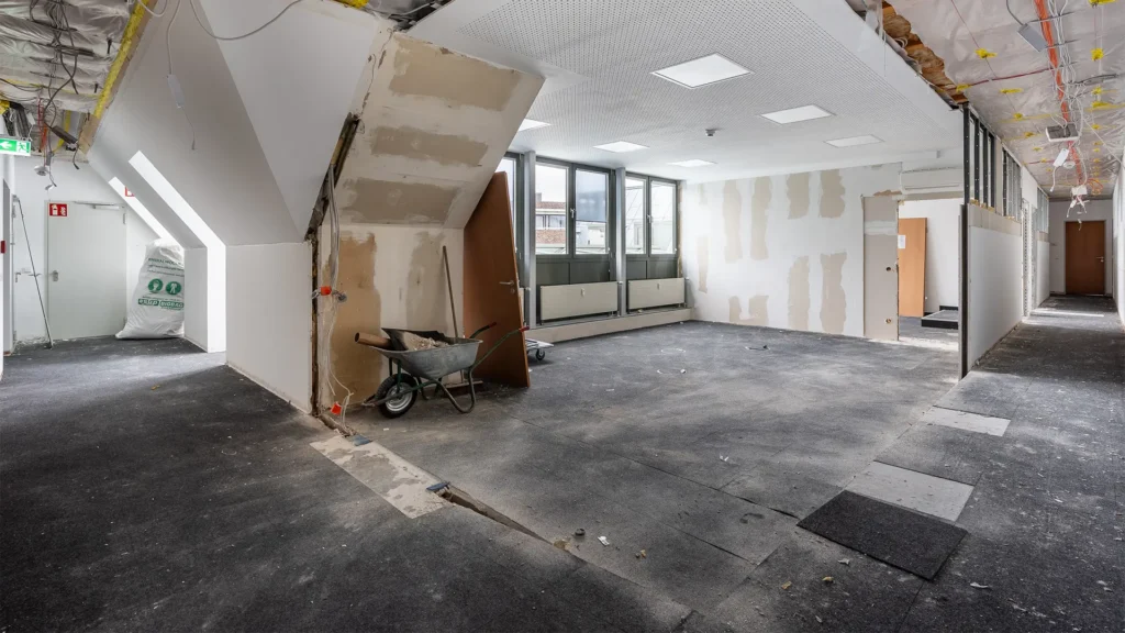Bürofläche während des Umbaus mit freigelegten Decken, Trockenbauarbeiten und unfertigen Räumen.